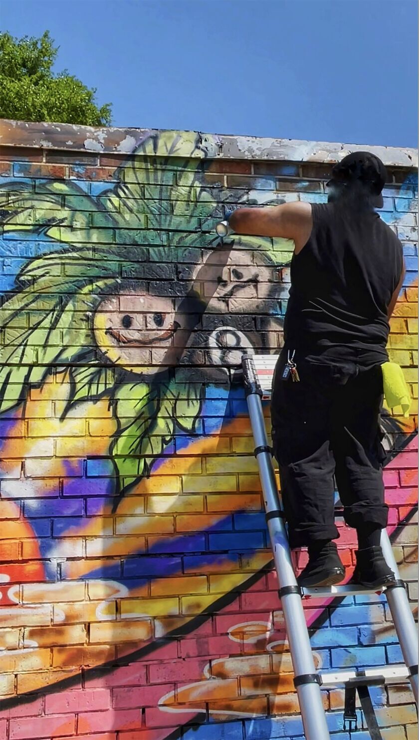 Ocean Muerto at work, painting a mural.