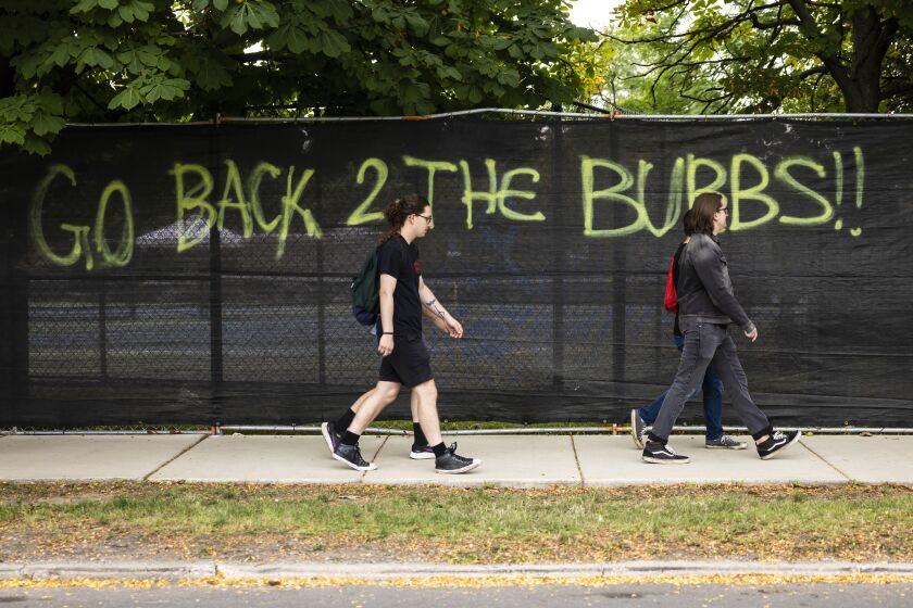 A message spray-painted on a fence surrounding Douglass Park, site of Riot Fest, says, “Go back 2 the burbs!!”