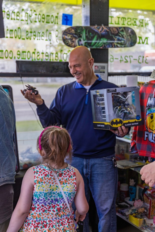 Dearborn Heights Mayor Bill Bazzi holds some Batman toys while a young girl looks on. (Kirsten Nordstrom - For MediaNews Group)