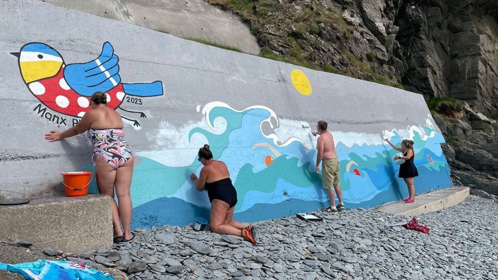 Swimmers painting the mural at Port Jack