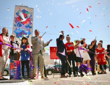 Confetti is visible in the air as people celebrate in front of a mural on a building.