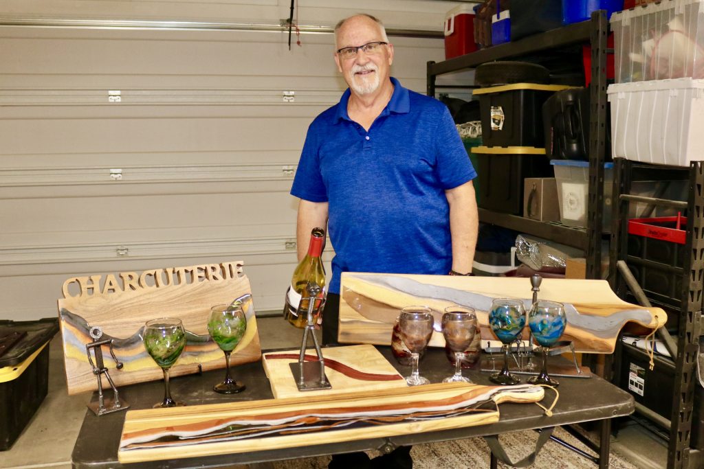 Kent Schlientz, owner of KC's Creations, takes a photo next to some of his hand-poured resin work and scrap metal art, St. George, Utah, Aug. 22, 2023 | Photo by Jessi Bang, St. George News