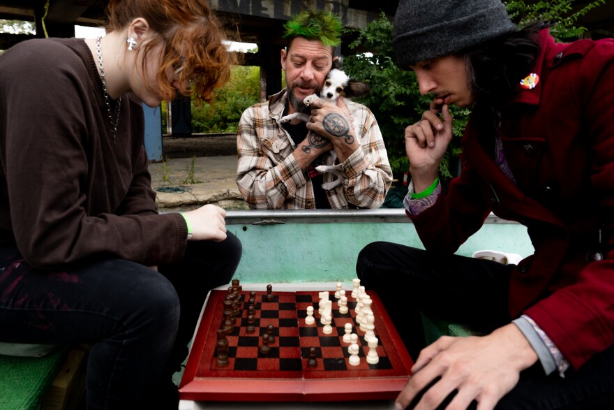 “Yo-Yo,” 45, of Dutchtown holds 4-month-old Papillon “Gizmo” as they watch Kate Humphreys, 18, of Granite City face off in a match of chess with her boyfriend, Victor Freeman, 21, of Compton Heights, while sitting in a boat on Sunday during the Artica Urban Art Festival along the Mississippi Riverfront in downtown St. Louis.