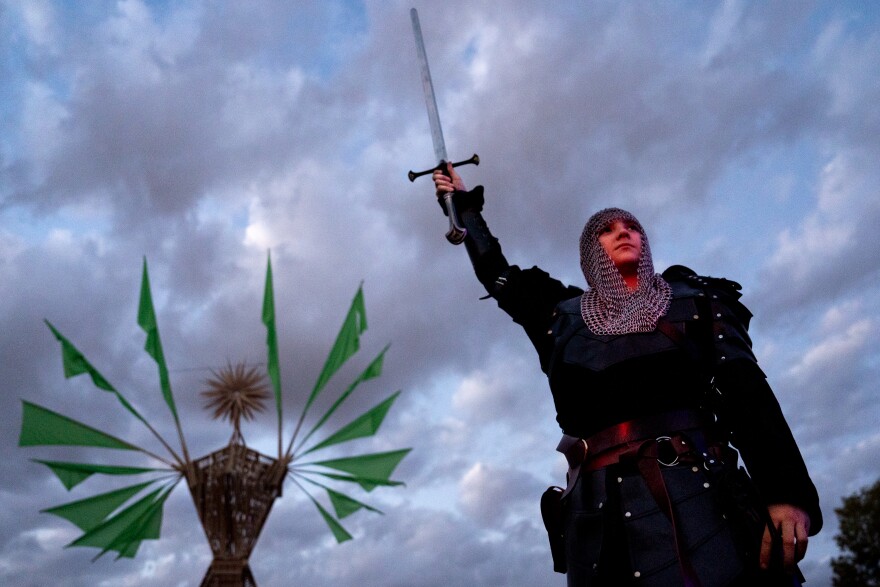 Sampson Norvell, 13, of Lemay Township, hoists up a sword on Sunday, Oct. 8, 2023, ahead of “Our Lady of Artica” being burned at the Artica Urban Art Festival along the Mississippi Riverfront in downtown St. Louis.