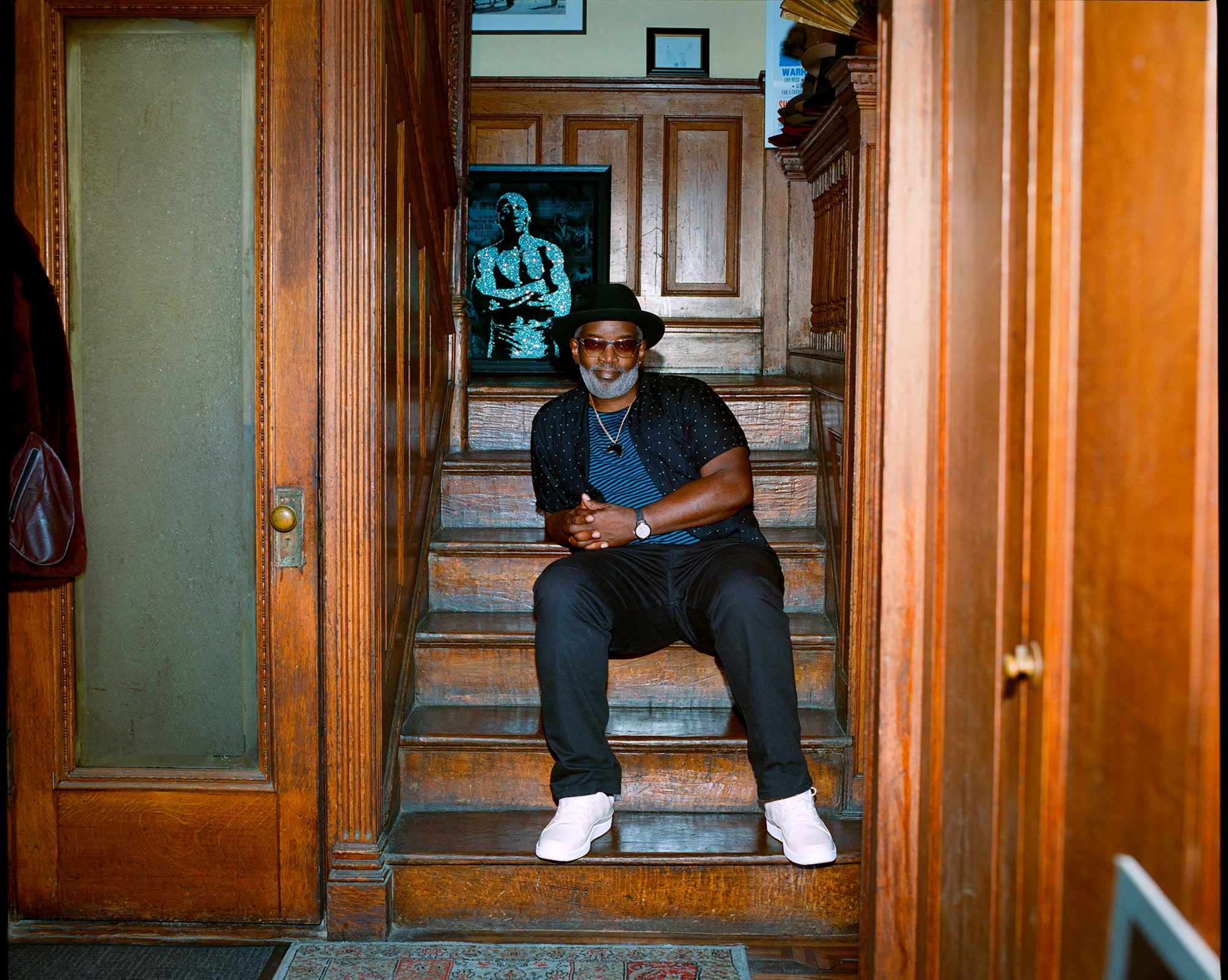 Fred Brathwaite  in his Harlem home with a velvet print from his series on boxer Jack Johnson. Watch by Omega.