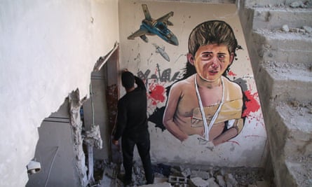 A Palestinian man stands next to a mural painted on the destroyed house in Deir al-Balah, Gaza.
