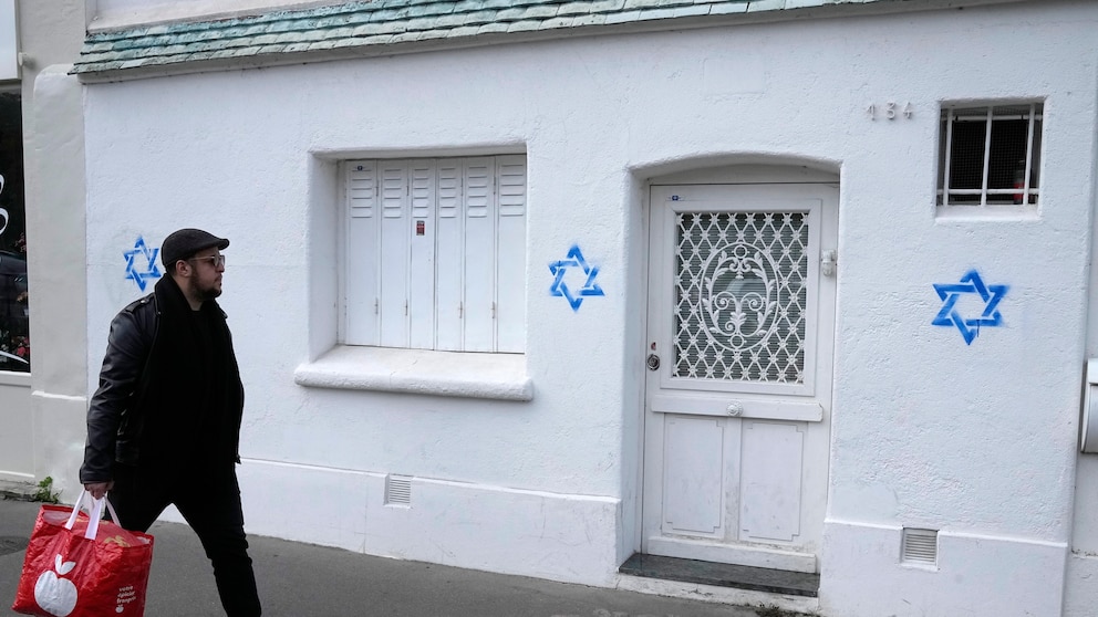 A man walks by Stars of David tagged on a wall Tuesday, Oct. 31, 2023 in Paris. Paris police chief Laurent Nunez described the graffiti as anti-Semitic and said police are investigating. (AP Photo/Michel Euler, Pool)