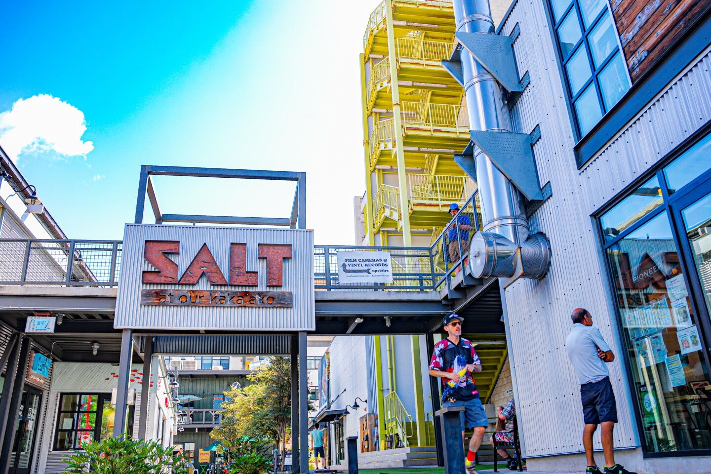 View of SALT signage and yellow stairs at Our Kakaako complex with restaurants, and retail stores. 
