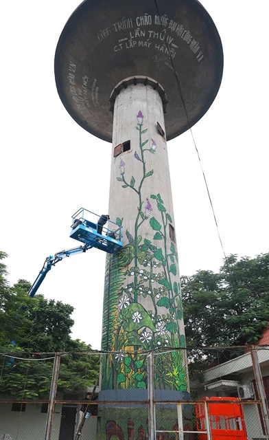 Artists put final touches on water tower graffiti within the Gia Lam Train Factory.
