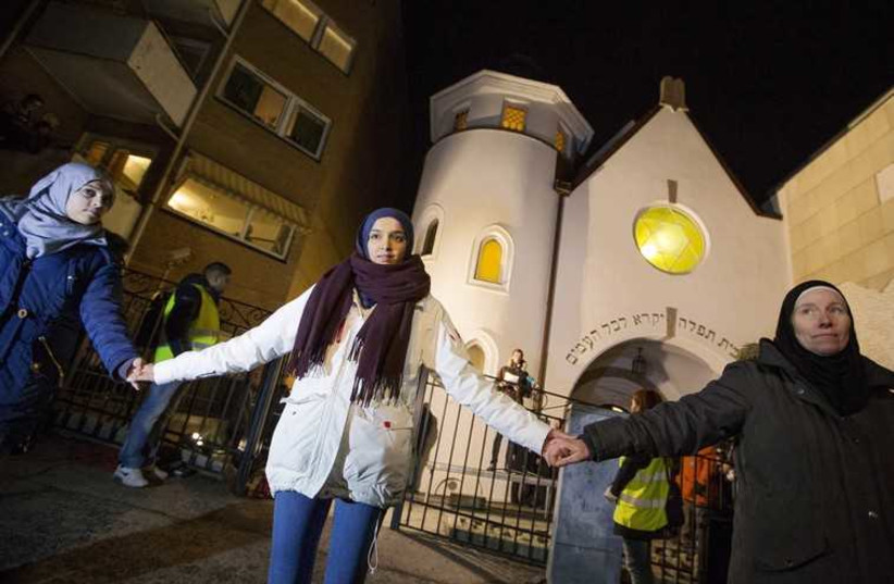 Muslim women join hands to form a human shield as they stand outside a synagogue in Oslo February 21, 2015. More than 1000 Muslims formed a human shield around Oslo's synagogue on Saturday. (credit: REUTERS)