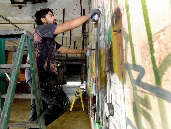 Graffiti artist Alex Smith works on one of his creations at the former Pillsbury Mills plant Wednesday, Nov. 8, 2023 as part of an art exhibit for Moving Pillsbury Forward.