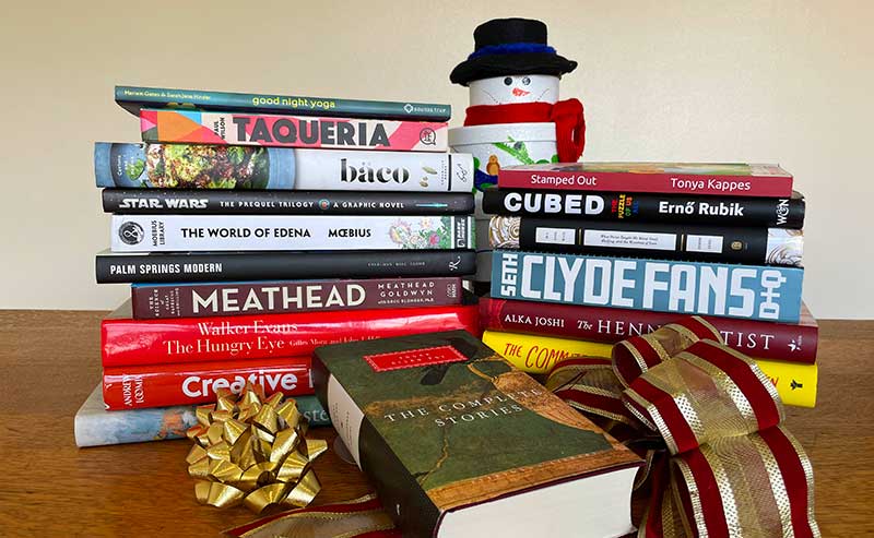 a stack of books with a christmas ornament and a ribbon
