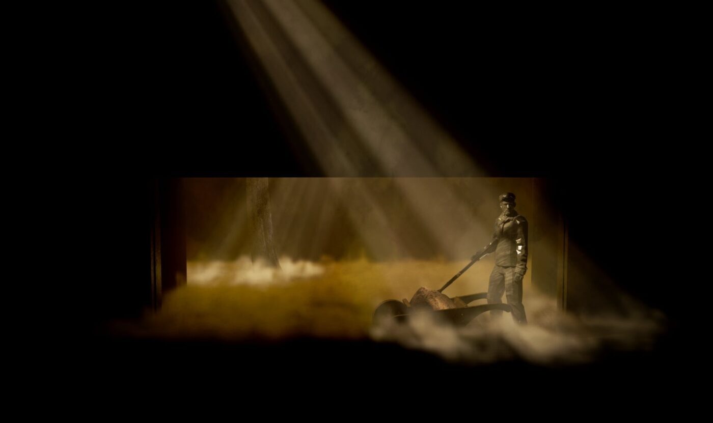 A digital rendering of a laborer against a rectangle of gold light on a dark stage.