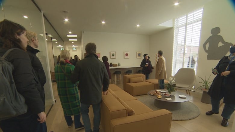 A lounge with couches in an office building. People are eating and drinking - about a dozen of them.