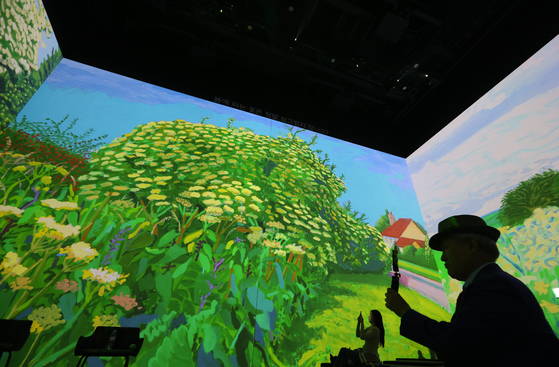 Reporters watch scenes from David Hockney's “Bigger & Closer (not smaller & further away)” exhibition at Lightroom Seoul in Gangdong District, eastern Seoul, on Oct. 30. [YONHAP]