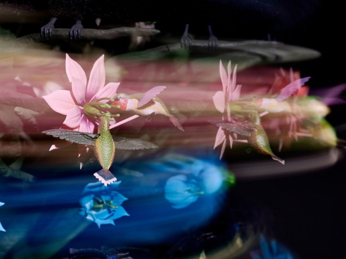 An intricate, colourful sculpture of humming birds hovering around exotic pink flowers