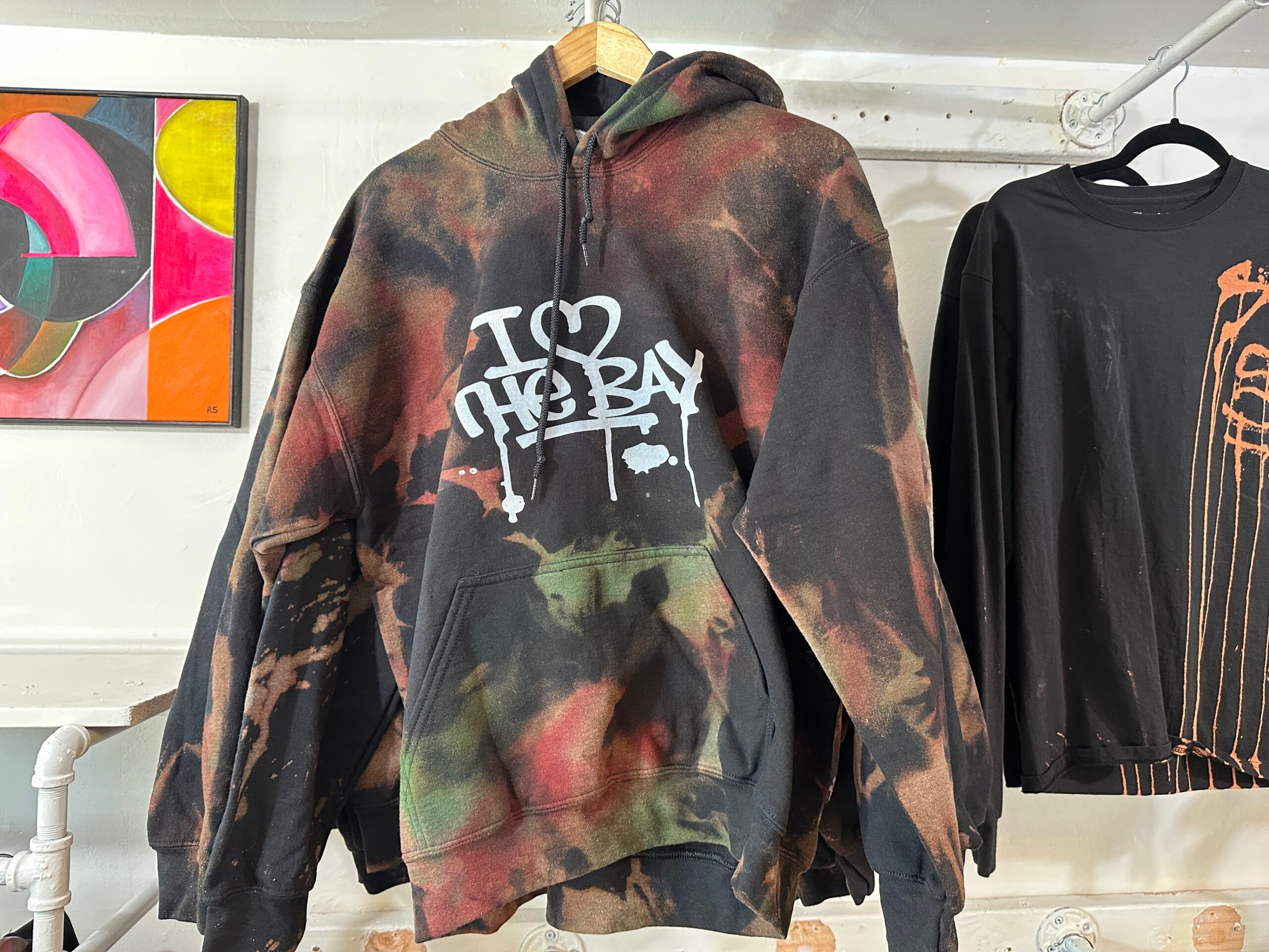A hoodie with "I Love the Bay" graffiti lettering hangs in an art and apparel shop on Valencia Street in San Francisco.