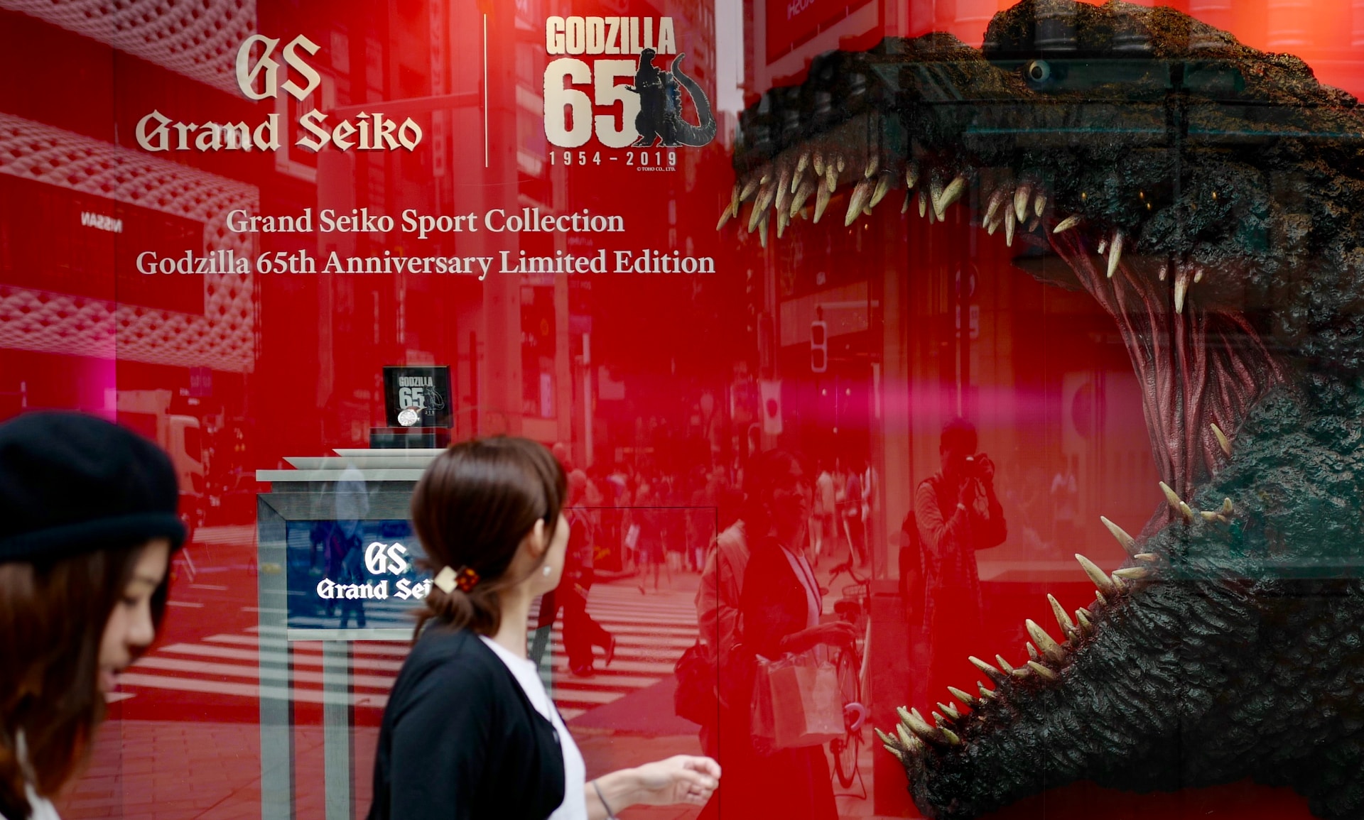 a statue of Godzilla A person passing by an image of Godzilla