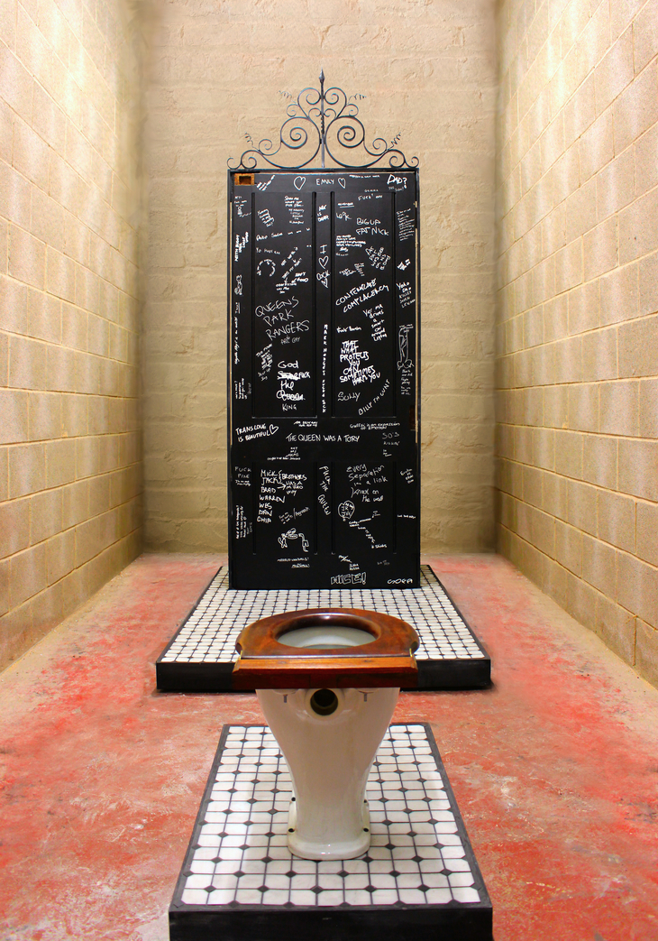 A black door scribbled with white graffiti behind a toilet
