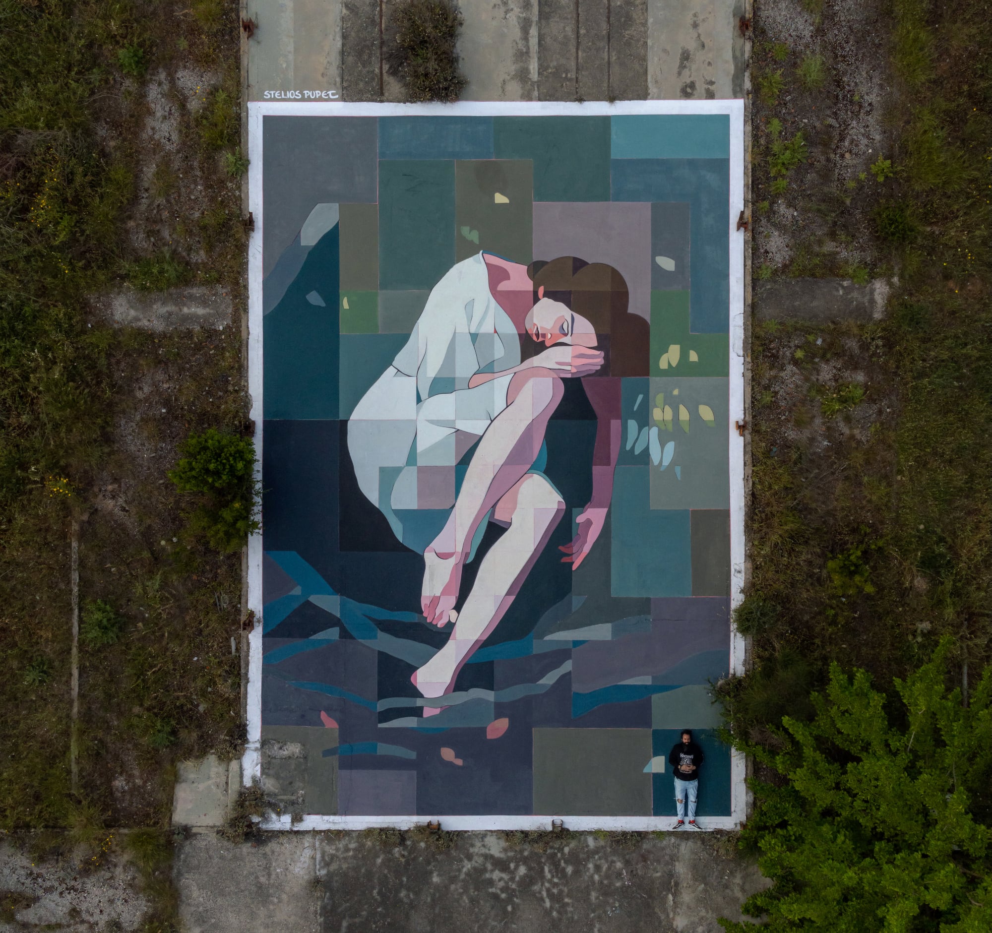 an aerial view of a mural of a woman curled up on a blue background