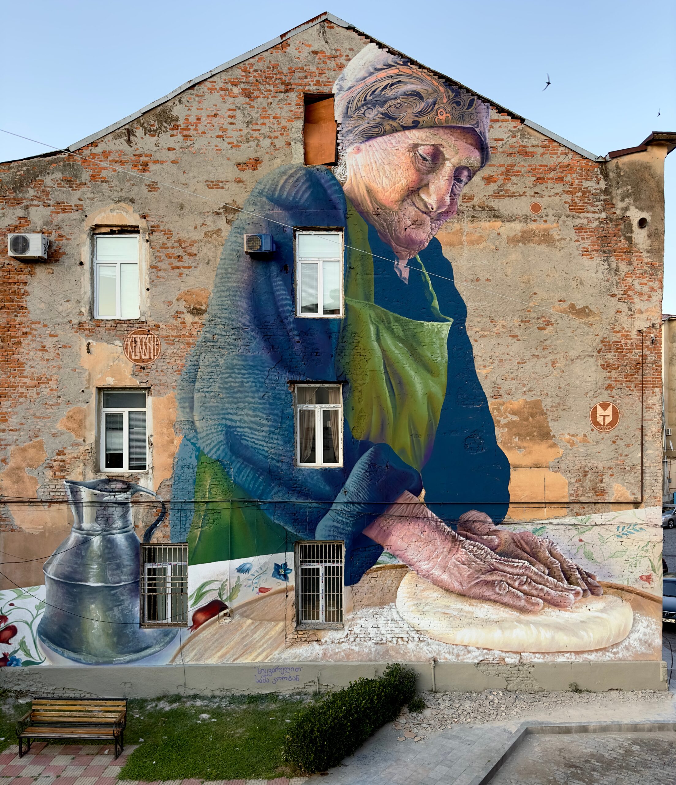an older woman presses dough while wearing a green apron