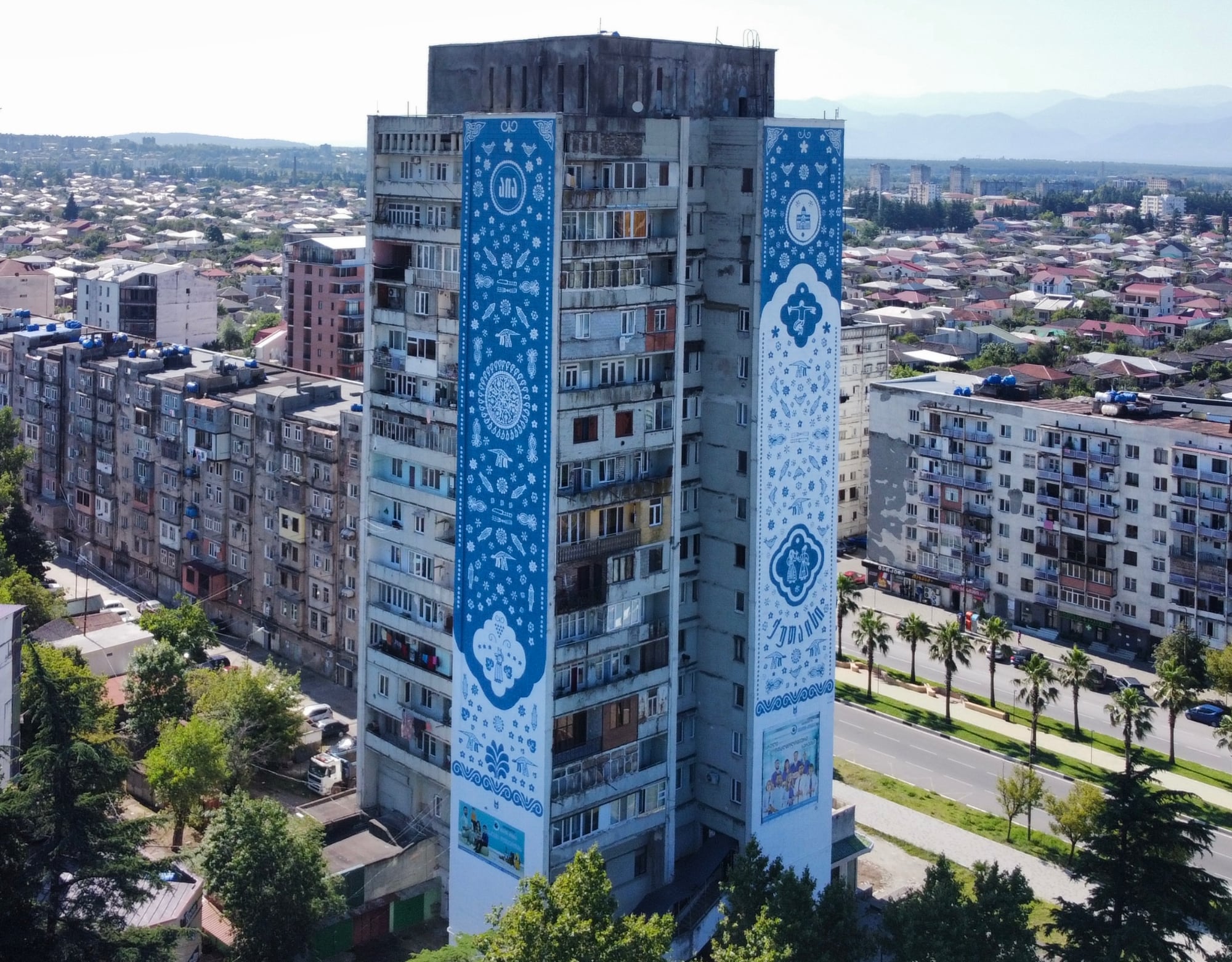 two blue and white patterned murals on sides of a building