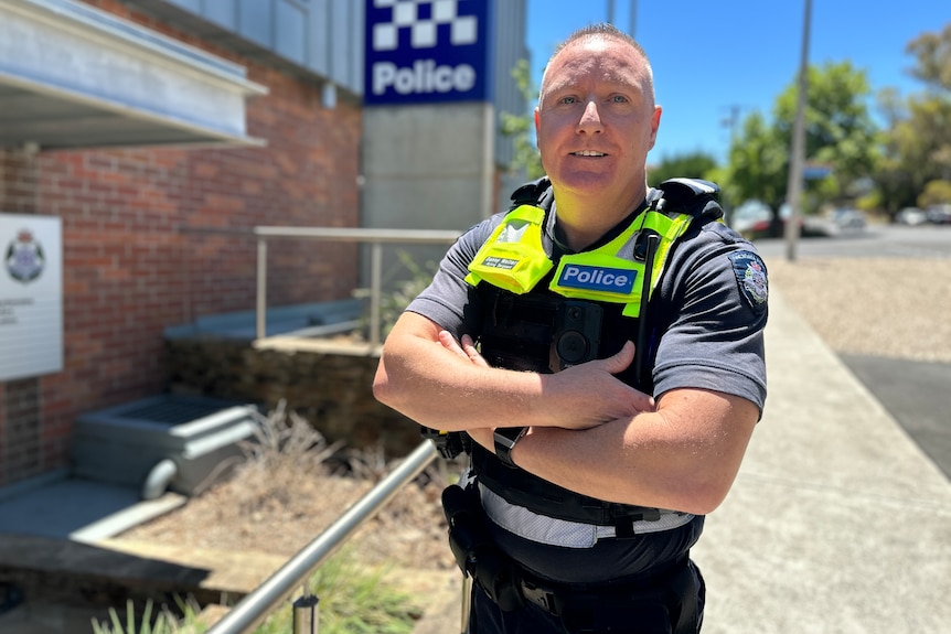 A police officer stands in front of a sign that says police