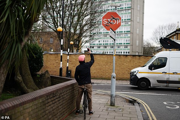 A man on a bike takes a photo of the artwork at the intersection of Southampton Way and Commercial Way in Peckham