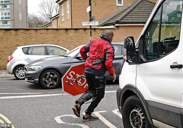 The man in the red jacket flees with the sign in front of stunned crowds who had gathered to look at it