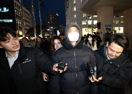 A man in his 20s accused of vandalizing the wall of Gyeongbok Palace on Sunday night returns home after being investigated by the police on Monday. [YONHAP]