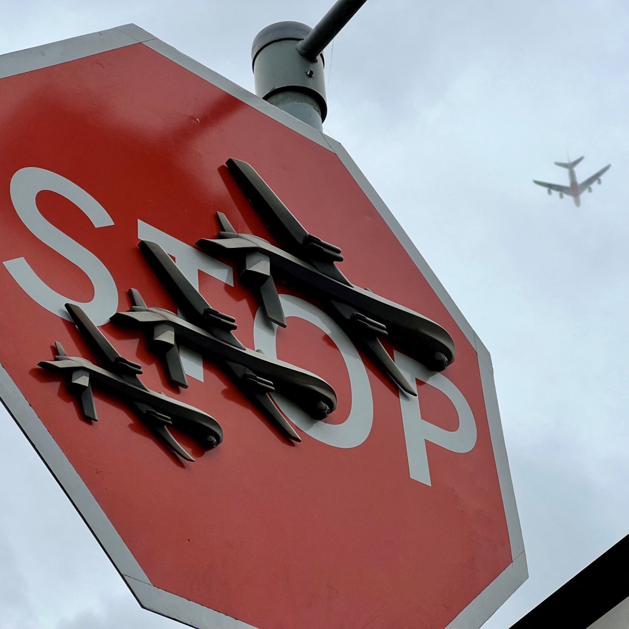 Aeroplane passes overhead as Banksy artwork depicting drones covers a stop sign in London. Photo: Joe Brown via Reuters