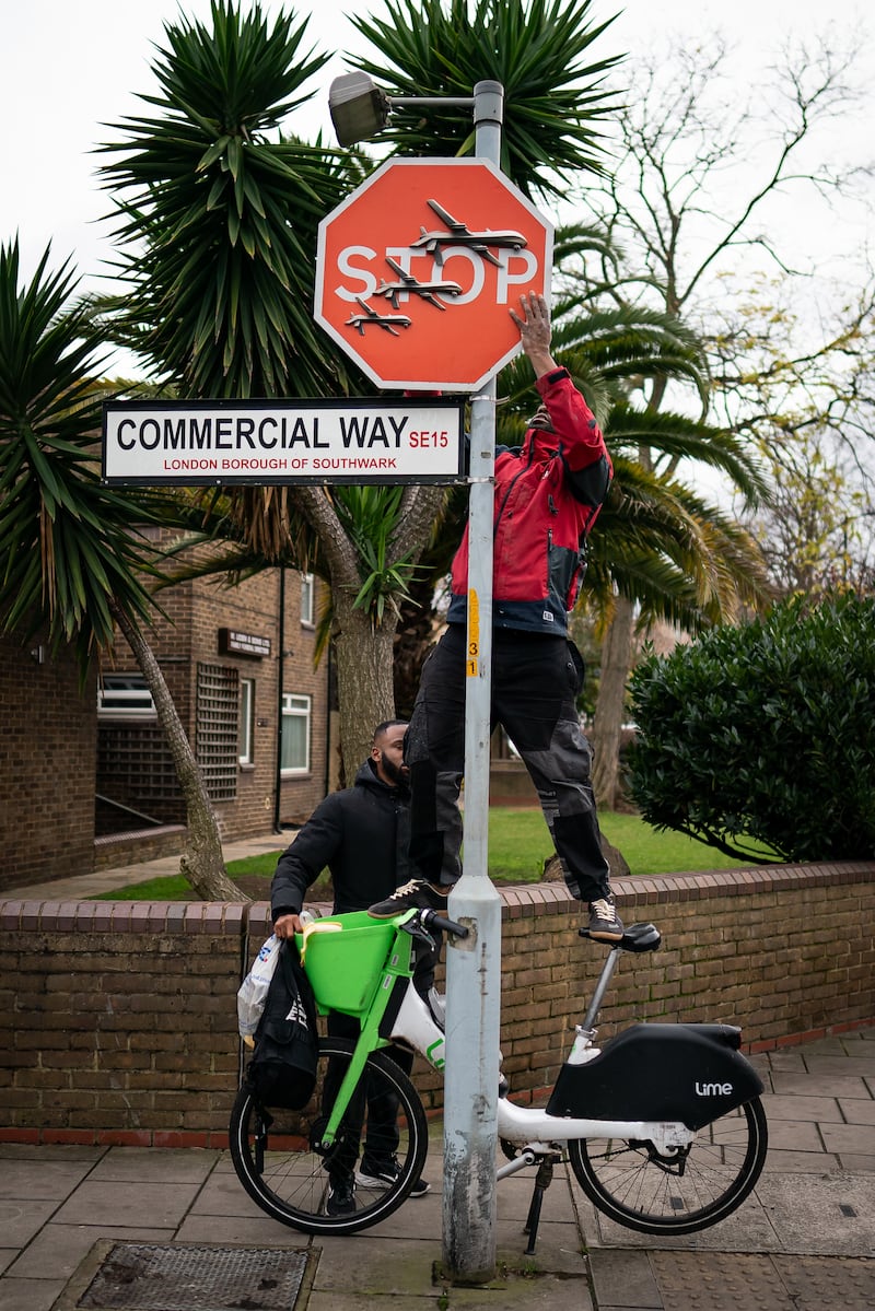A person removes an artwork by Banksy, which was unveiled at the intersection of Southampton Way and Commercial Way in Peckham, south-east London
