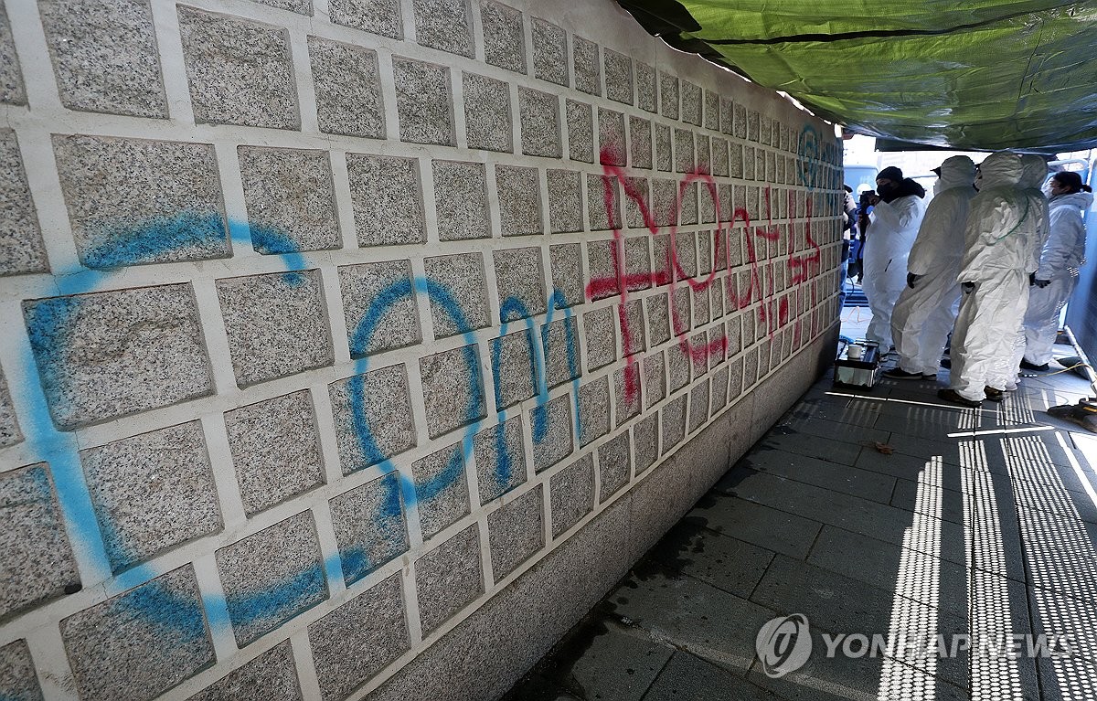 Workers remove graffiti sprayed on the walls of Gyeongbok Palace in Seoul on Dec. 17, 2023. (Pool photo) (Yonhap)