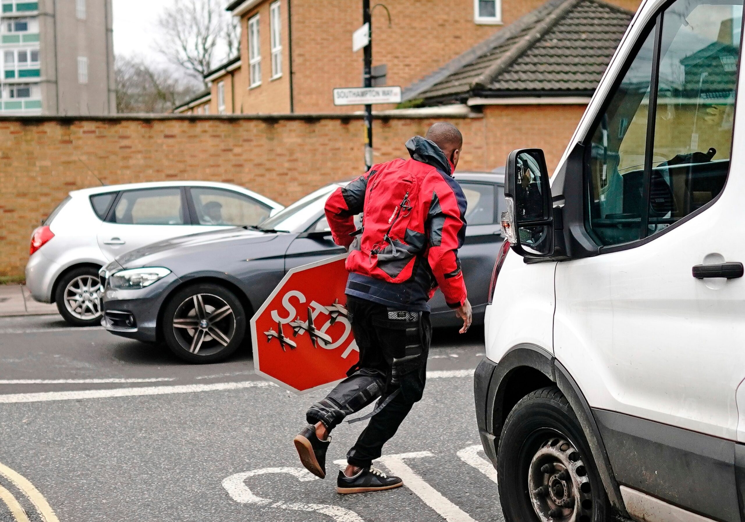 PHOTO: A person removes a piece of art work by Banksy, which shows what looks like three drones on a traffic stop sign, which was unveiled at the intersection of Southampton Way and Commercial Way in Peckham, London, on Dec. 22, 2023.