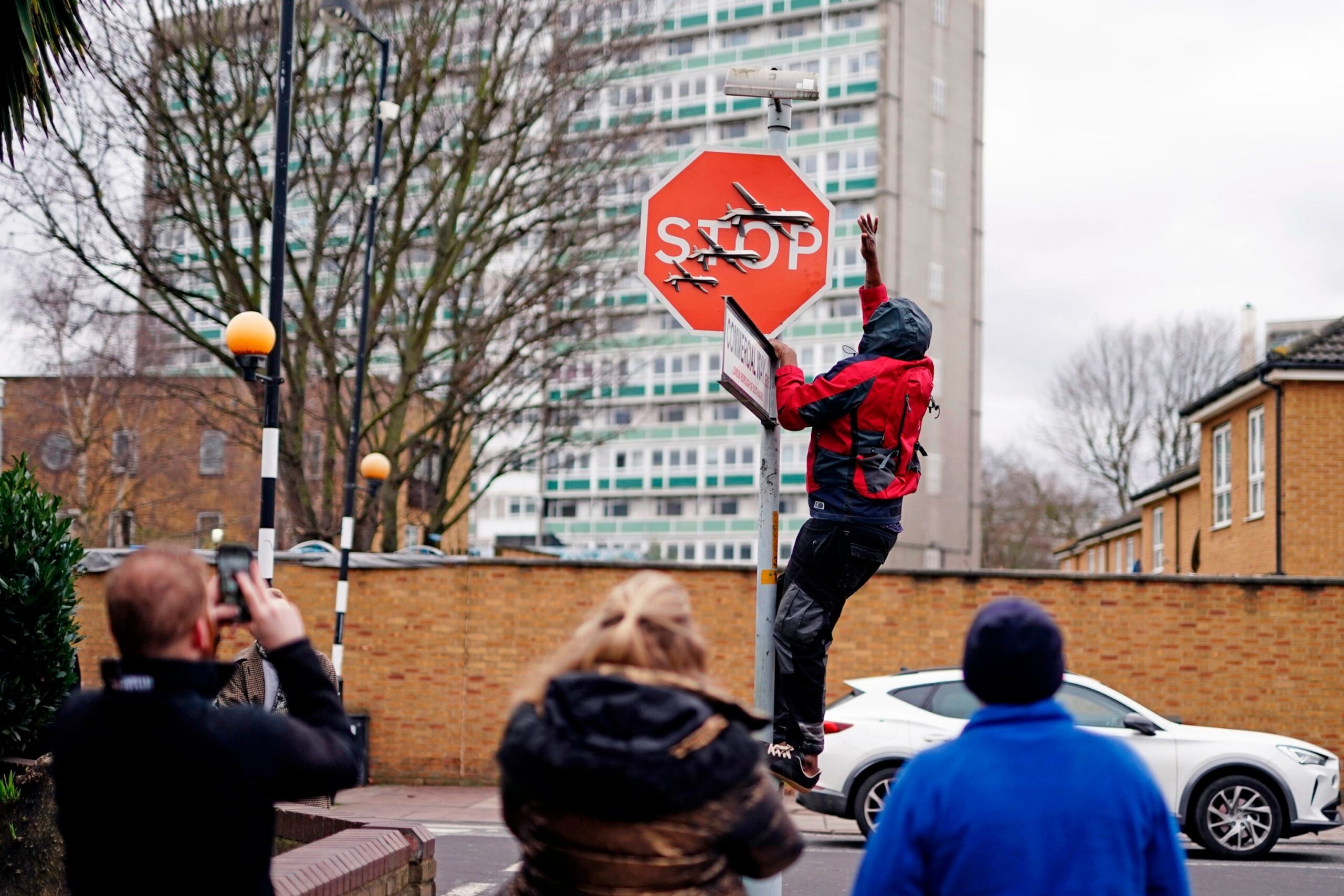 PHOTO: A person removes a piece of art work by Banksy, which shows what looks like three drones on a traffic stop sign, which was unveiled at the intersection of Southampton Way and Commercial Way in Peckham, London, on Dec. 22, 2023.