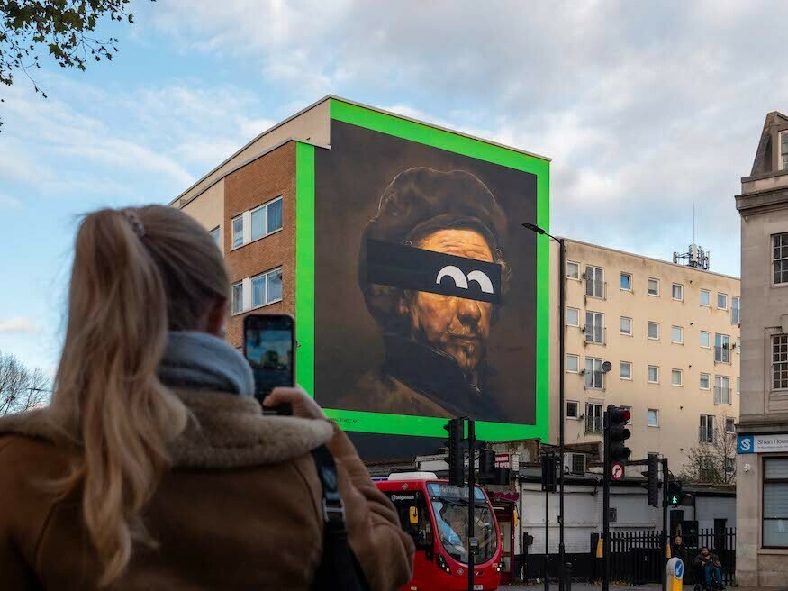 Woman takes a photo of a mural of rembrandt in hackney