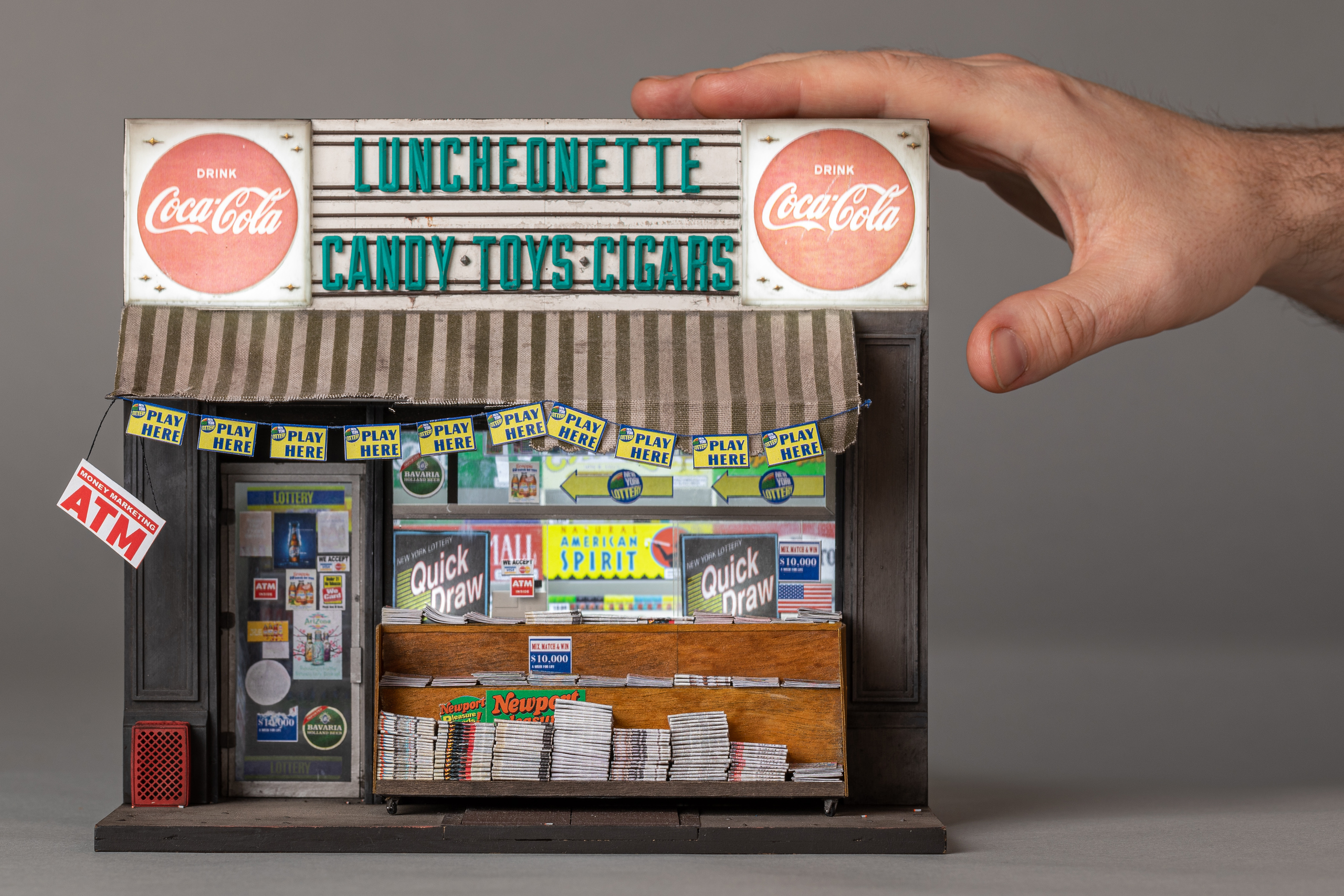 A scale model of a vintage luncheonette. A hand holds it for scale.