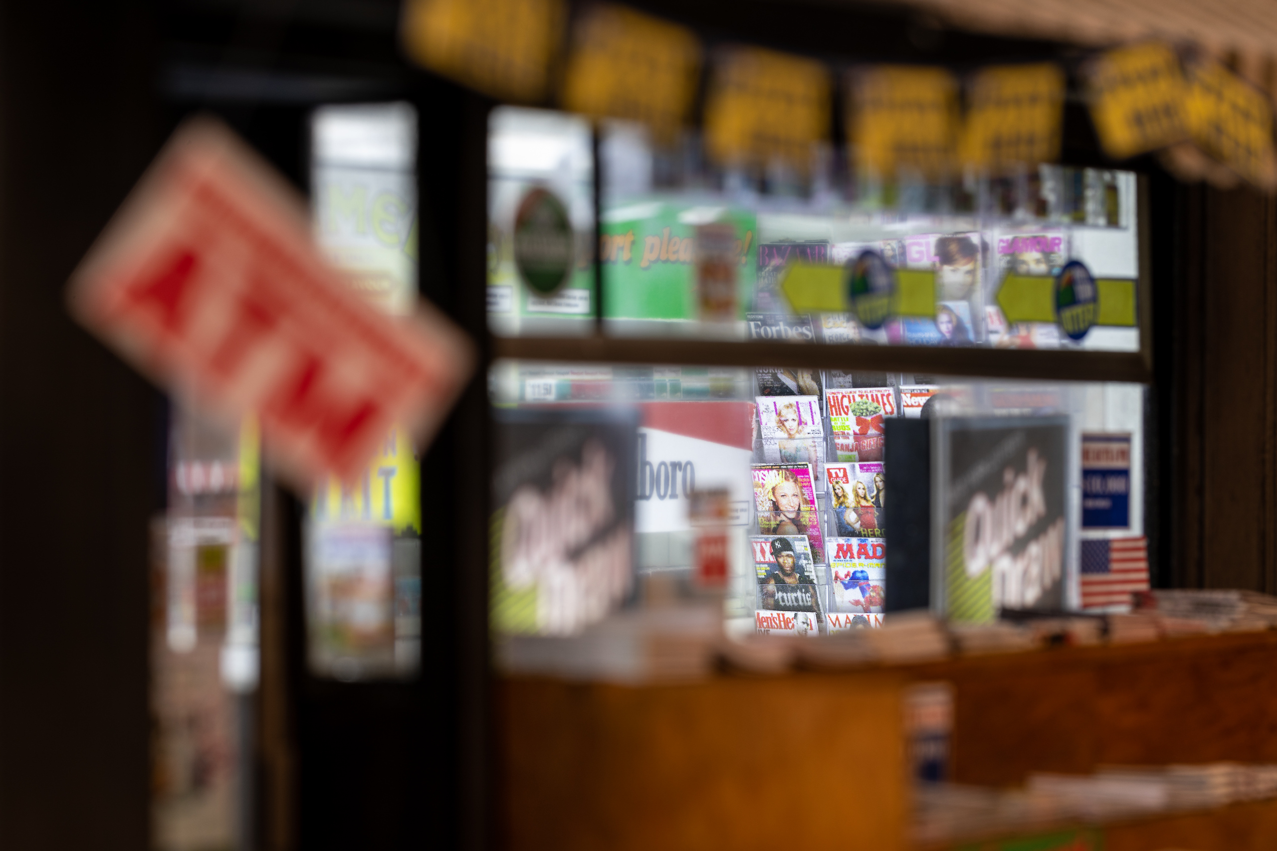 Details of a scale model of a newsstand, focused on tiny magazines inside the shop.