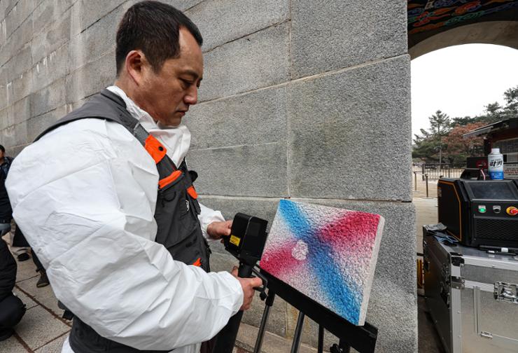 An official at the National Research Institute of Cultural Heritage demonstrates how laser equipment was used to remove paint from the walls of Gyeonbok Palace at the site in central Seoul, Thursday. Korea Times photo by Shim Hyun-chul
