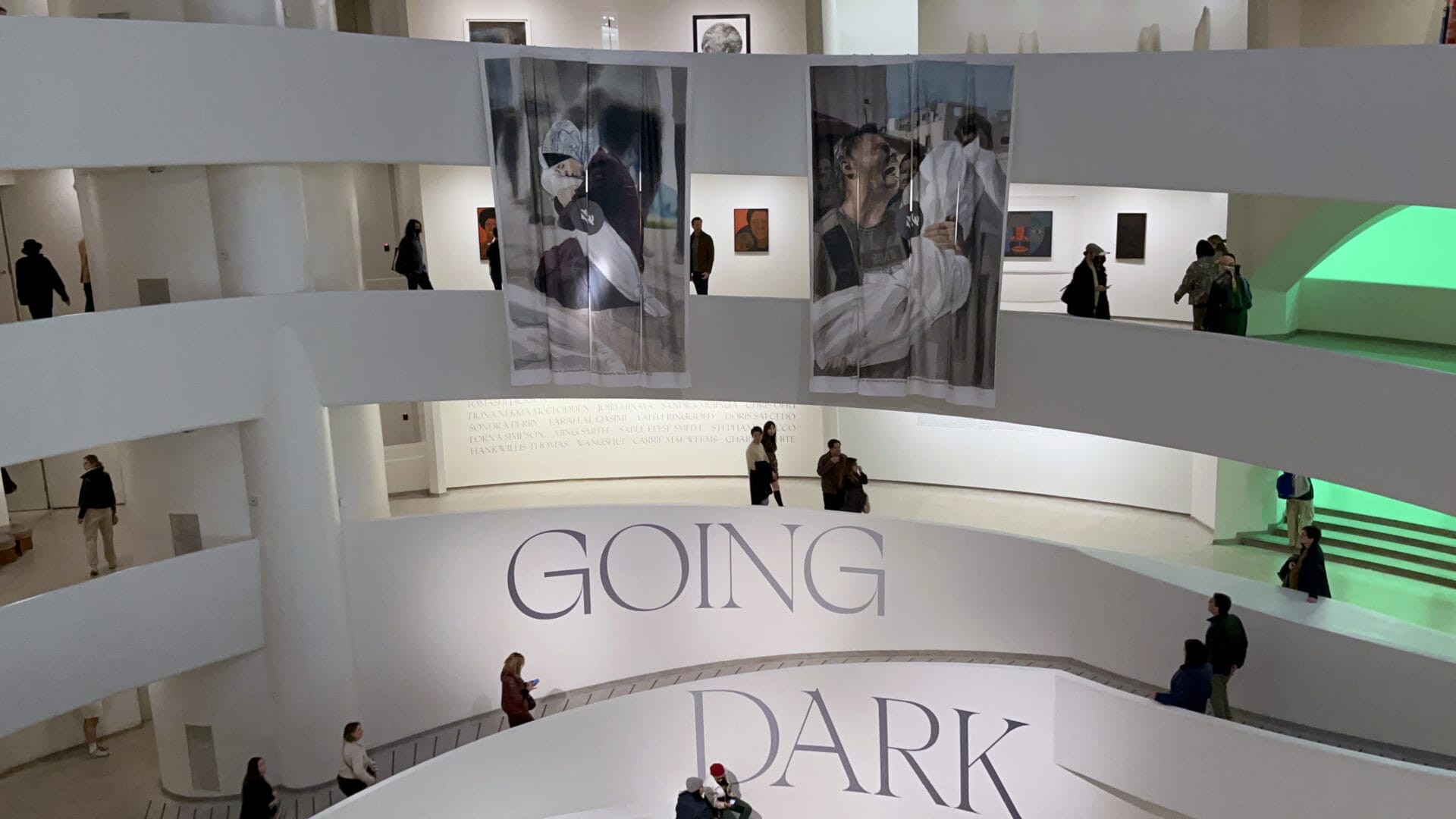 Two large posters hang at the Guggenheim, draping an area that showcases several levels of the museum.
