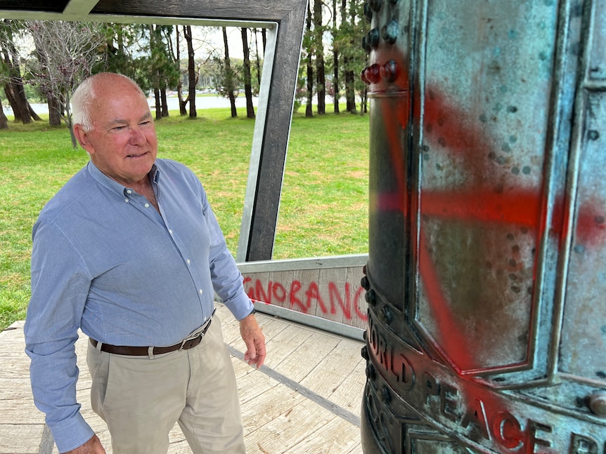 A man stands next to graffiti 
