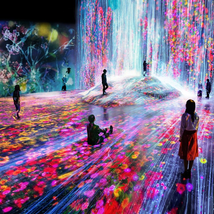 People stand in a room where floral patterns are projected onto the walls and floor