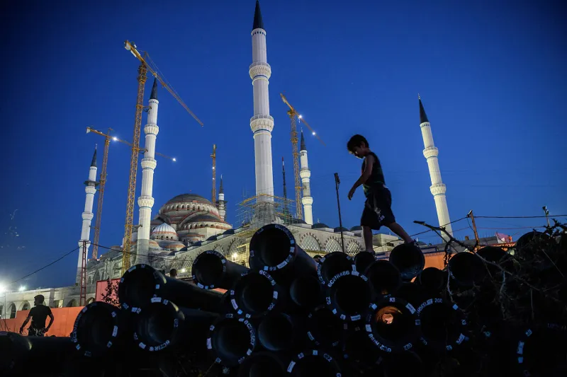 A young boy at dusk walks on top of a stack of construction materials outside the new Camlica mosque in Istanbul.