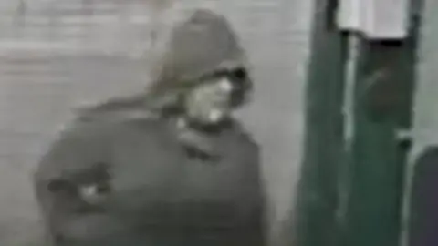 Met Police A blurry black and white image of a white man wearing a dark hooded jacket