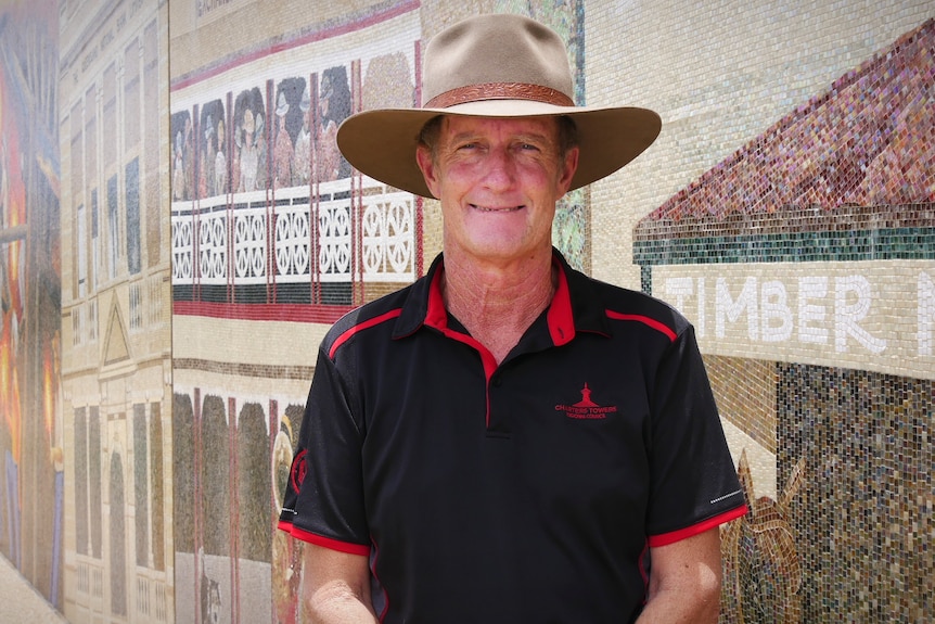 A man in a hat in front a mosaic wall