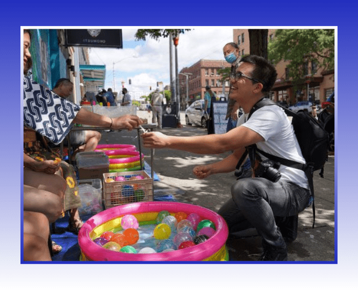 Man crouched outside getting something handed to him