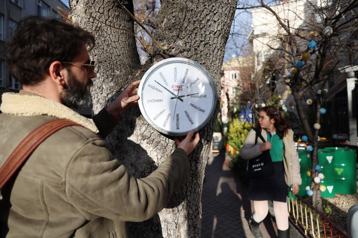 Hikmeti Tabiyeci installs one of his creations titled <em>political clock</em>&nbsp;on a tree on a street in Ankara.