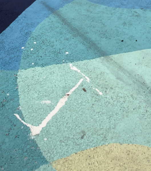 The letter “J” or a similar shape, is also drawn nearby, in the same white paint. 