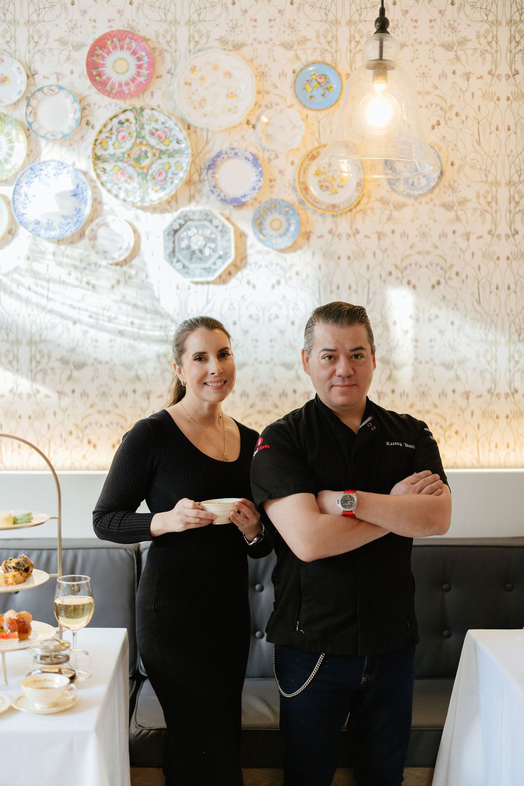 A woman in a black dress posing to the left of a man in a black chef’s shirt.