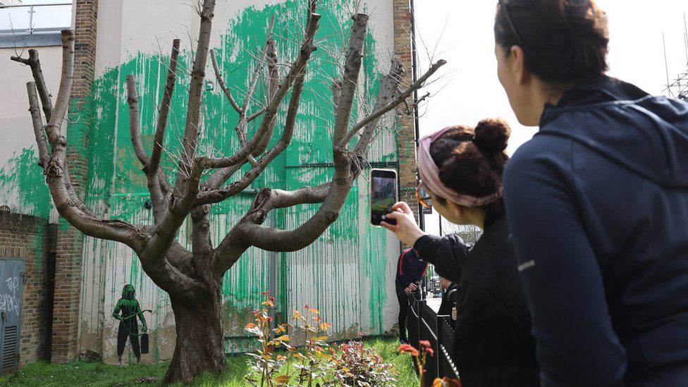 photograph shows onlookers next to the new banksy mural